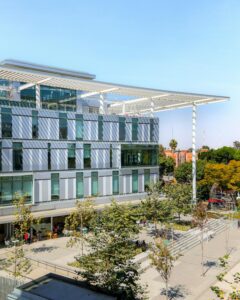 A contemporary campus building with glass features and lush surroundings, capturing a vibrant academic atmosphere.